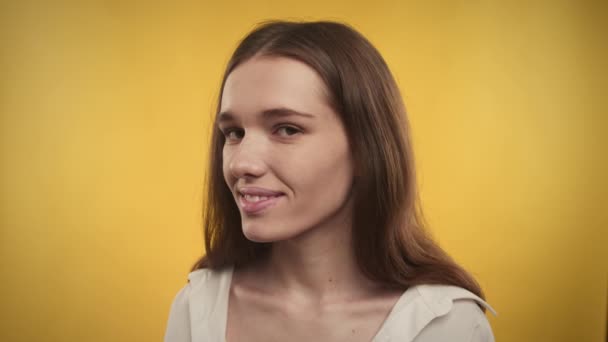 Portret van een jonge volwassen blanke vrouw lacht op een heldergele achtergrond — Stockvideo
