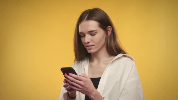 Jeune femme caucasienne adulte est surpris par le message sur smartphone sur un fond jaune vif — Video