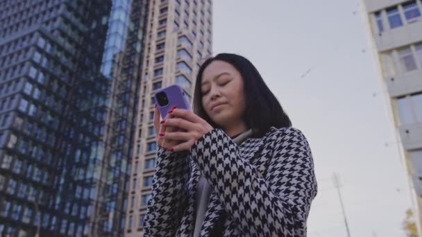 Giovane donna asiatica adulta che naviga sul suo smartphone in centro — Video Stock