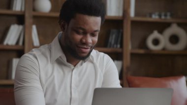 Genç yetişkin girişimci ofisinde dizüstü bilgisayarla mutlu bir şekilde çalışıyor.