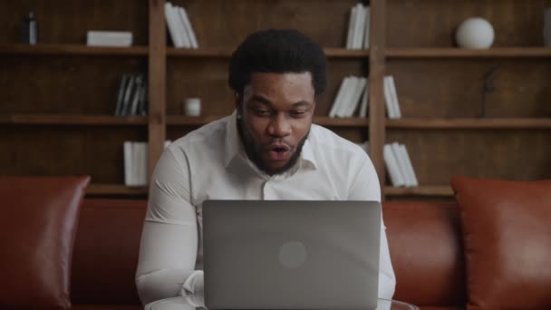 Joven hombre de negocios adulto recibiendo buenas noticias en su computadora portátil en la oficina loft — Vídeos de Stock