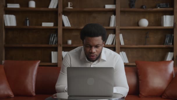 Junger erwachsener schwarzer Mann erhält gute Nachrichten auf seinem Laptop — Stockvideo