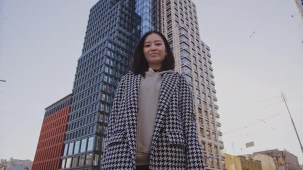 Low-angle portret van een jonge volwassen aziatische vrouw in het centrum van de wijk — Stockvideo