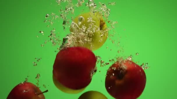 Grupo de manzanas rojas y verdes mezcladas que caen al agua en cámara lenta — Vídeo de stock