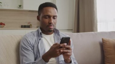 Afrikalı bir Amerikalının portresi. Dairesinde akıllı bir telefonla düşünüyor ve daktilo yazıyor.