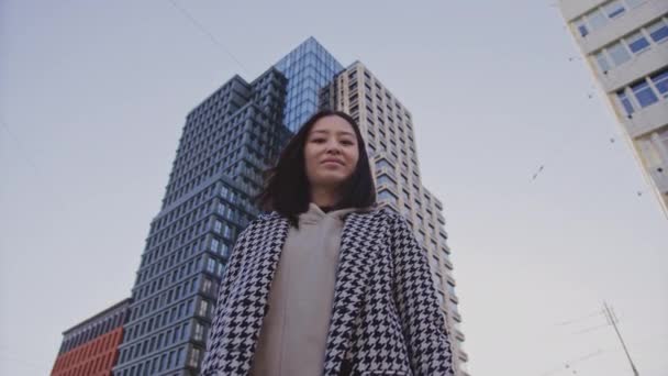 Low-angle portret van een jonge volwassen aziatische vrouw in het centrum van de wijk — Stockvideo