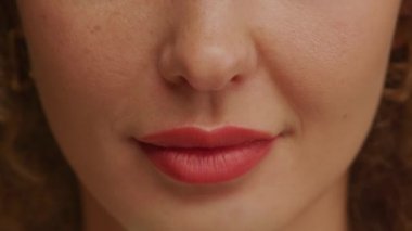 Mükemmel doğal dişleri ve parlak rujuyla büyüleyici bir kadın gülüşüne yaklaş.
