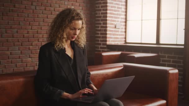 Mladá stylová podnikatelka pracující na notebooku v podkrovním bytě s červenou cihlovou zdí — Stock video