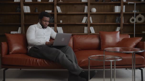 Junger erwachsener Unternehmer arbeitet am Laptop auf einem Sofa in seinem Loft-Büro — Stockvideo