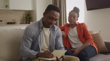 20 'li yaşlardaki Afro-Amerikan ailesi planlarını tartışıyor ve not defterine not ediyor.