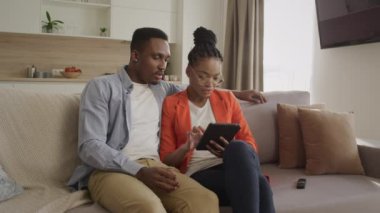 Genç aile internet üzerinden alışveriş yaparken tablet bilgisayarda sörf yapıyor.