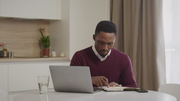 Genç Afrikalı Amerikalı adam faturalarını kontrol ediyor ve ev harcamalarını yönetiyor. — Stok video