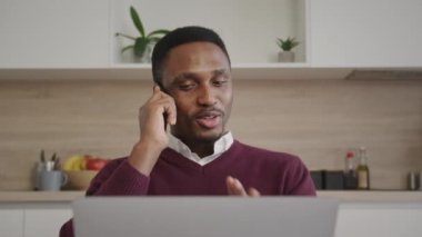 Genç ve yetişkin bir iş adamının dizüstü bilgisayarının önünde telefonla konuşması.