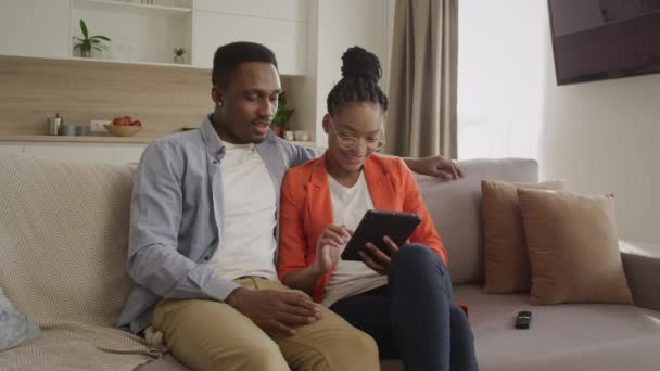 젊은 아프리카 계 미국인 가족 이 온라인 쇼핑을 하는 동안 태블릿 컴퓨터로 웹 서핑을 하고 있다. — 비디오