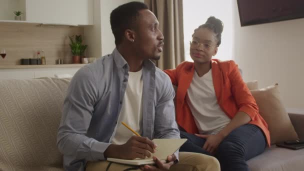20多岁的非洲裔美国家庭正在讨论他们的计划，并将其记录在记事本上 — 图库视频影像