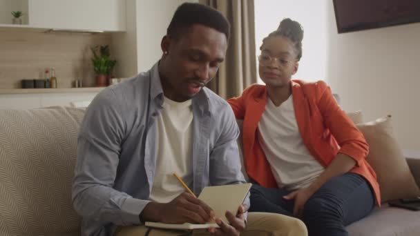 20s afro-americanos família está discutindo seus planos e observá-los para baixo no bloco de notas — Vídeo de Stock