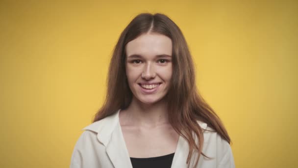 20 's jonge volwassen vrouw glimlachen op camera op een heldere gele achtergrond — Stockvideo