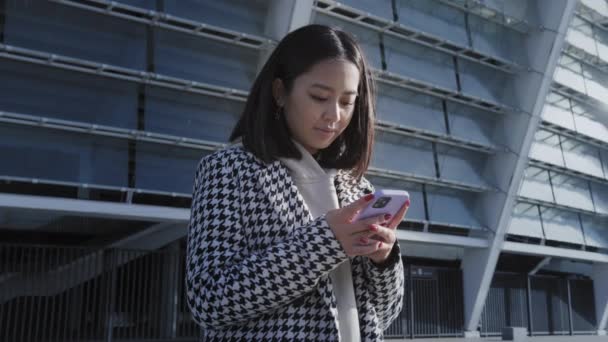 시내에 있는 스마트폰으로 타자를 치는 젊은 성인 여성 — 비디오