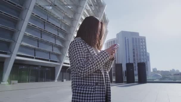 Mujer joven adulta escribiendo en su teléfono inteligente en el centro de la ciudad — Vídeos de Stock