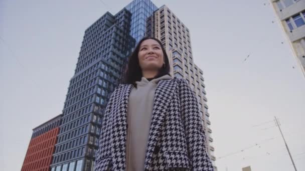 Low-angle portret van een jonge volwassen aziatische vrouw in het centrum van de wijk — Stockvideo