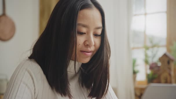 Close-up portret van een jong volwassen aziatische vrouw met beugels glimlachen terwijl het werken op een laptop — Stockvideo