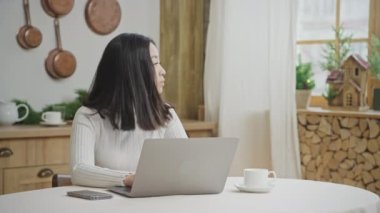 Evde dizüstü bilgisayarla çalışan 20 'li yaşlarda bir kadının portresi.