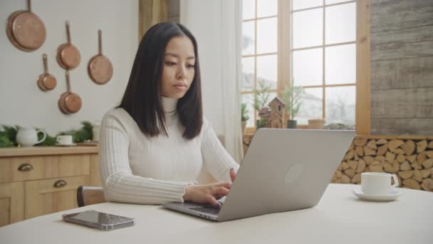 Mujer joven adulta trabajando centrada en su portátil en interiores — Vídeos de Stock