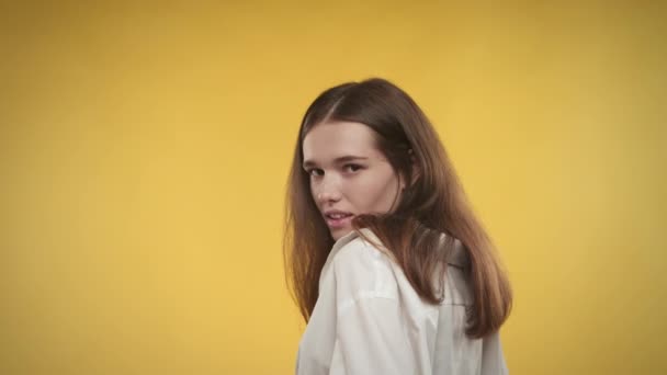 Молодая белая женщина интересуется ярко-желтым фоном в студии — стоковое видео