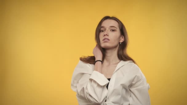 Retrato de uma mulher caucasiana dos anos 20 sorrindo para a câmera em um fundo amarelo brilhante — Vídeo de Stock