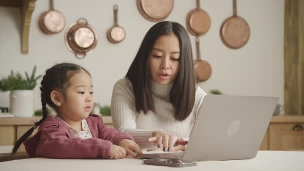 女儿在母亲的笔记本电脑上打字，而母亲则解释如何使用电脑 — 图库视频影像