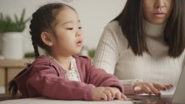 Meraklı kız, annesiyle birlikte dizüstü bilgisayarı inceliyor.