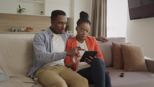 若いアフリカ系アメリカ人の家族はオンラインショッピング中にタブレットコンピュータでウェブをサーフィンしています — ストック動画