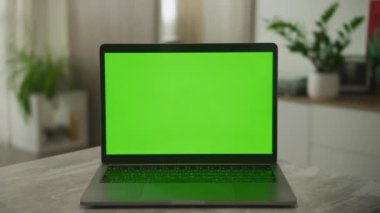 Static shot of a laptop with a green screen on a desk in modern apartment