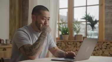 Genç Asyalı bir adam laptopunun önünde bir çözüm bulmak için ara verir.