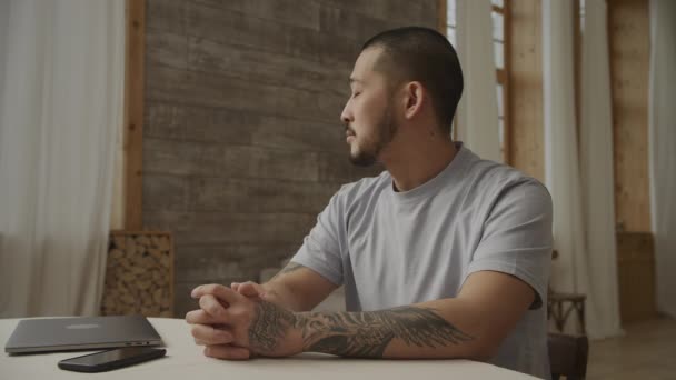 Porträt eines jungen erwachsenen asiatischen Unternehmers, der drinnen vor seinem Laptop sitzt — Stockvideo