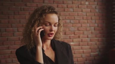 Genç, kıvırcık, sarışın, 30 'lu yaşlardaki iş kadını çatı katında telefonla konuşuyor.