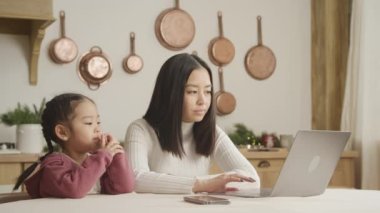 Anne ve kızı evde dizüstü bilgisayarda geziniyor.