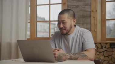 İçerideki dizüstü bilgisayarla Asyalı bir adam görüntülü görüşme yapıyor.