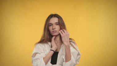 Young adult caucasian woman is ... on a bright yellow background in studio