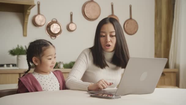年轻的母亲和女儿在屋里的笔记本电脑前交谈 — 图库视频影像