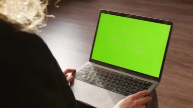 Kapalı alanda yeşil ekran krom anahtarı olan dizüstü bilgisayarı izleyen bir kadının fotoğrafını çek.