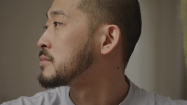 Крупним планом портрет молодого дорослого азіатського чоловіка, який посміхається на камеру в приміщенні — стокове відео