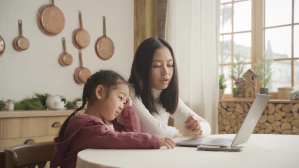 Mãe ensinando sua filha uma lição em seu laptop dentro de casa — Vídeo de Stock
