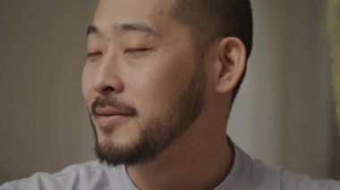 Close up portrait of a young adult asian man smiling at camera indoors