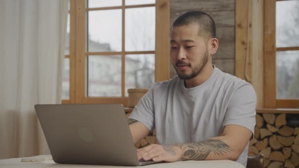 Asiatische Männergruß auf einem Videoanruf mit Laptop drinnen — Stockvideo