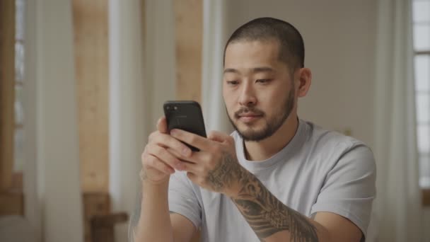 Primer plano de un asiático tatuado hombre ganar y lograr algo en su teléfono inteligente — Vídeos de Stock