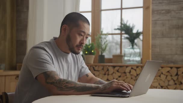 Jong volwassen aziatische ondernemer werken op zijn laptop binnen — Stockvideo