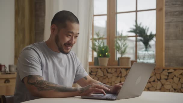 20-talet tottooed man bläddrar på sin bärbara dator när du handlar online inomhus — Stockvideo