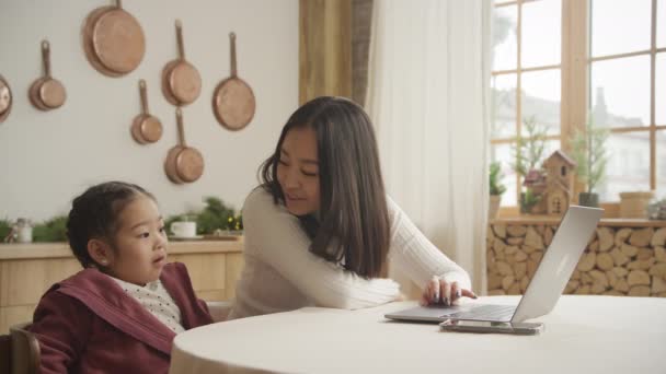 Mãe ensinando sua filha uma lição em um laptop dentro de casa — Vídeo de Stock