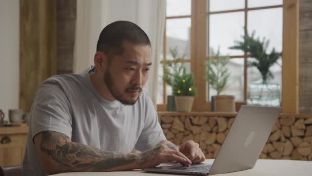 若い大人の入れ墨起業家読書メッセージ上の彼のラップトップ室内で彼のアパート — ストック動画